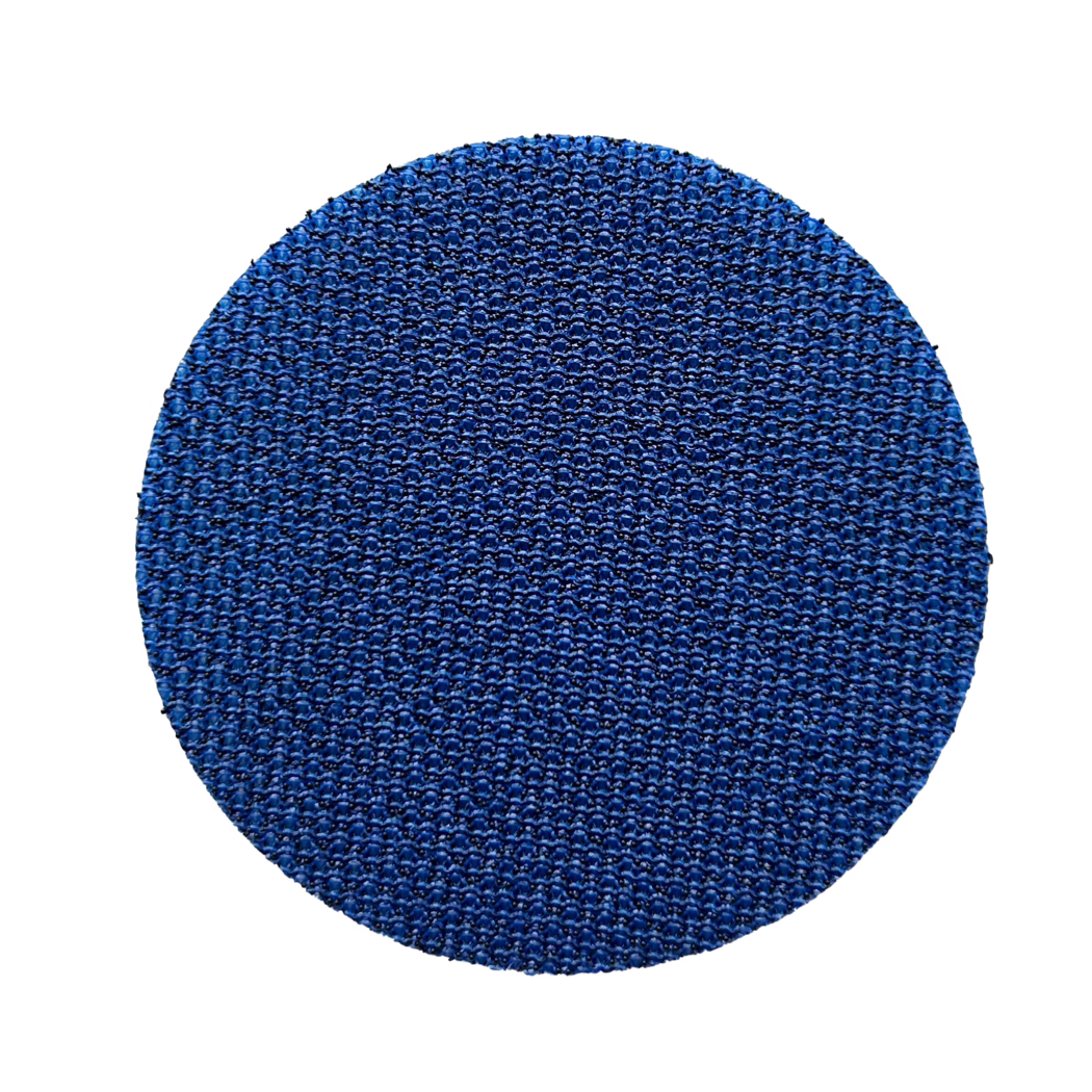 Klettauflage_60mm_selbstklebend_freigestellt Gros plan d'une surface circulaire texturée bleue occupant la moitié inférieure de l'image, montrant un motif dense et répétitif semblable à un tissage avec de petites bosses surélevées et des reflets brillants sur fond blanc.